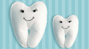 Two soft toy teeth with smiling faces on a striped background