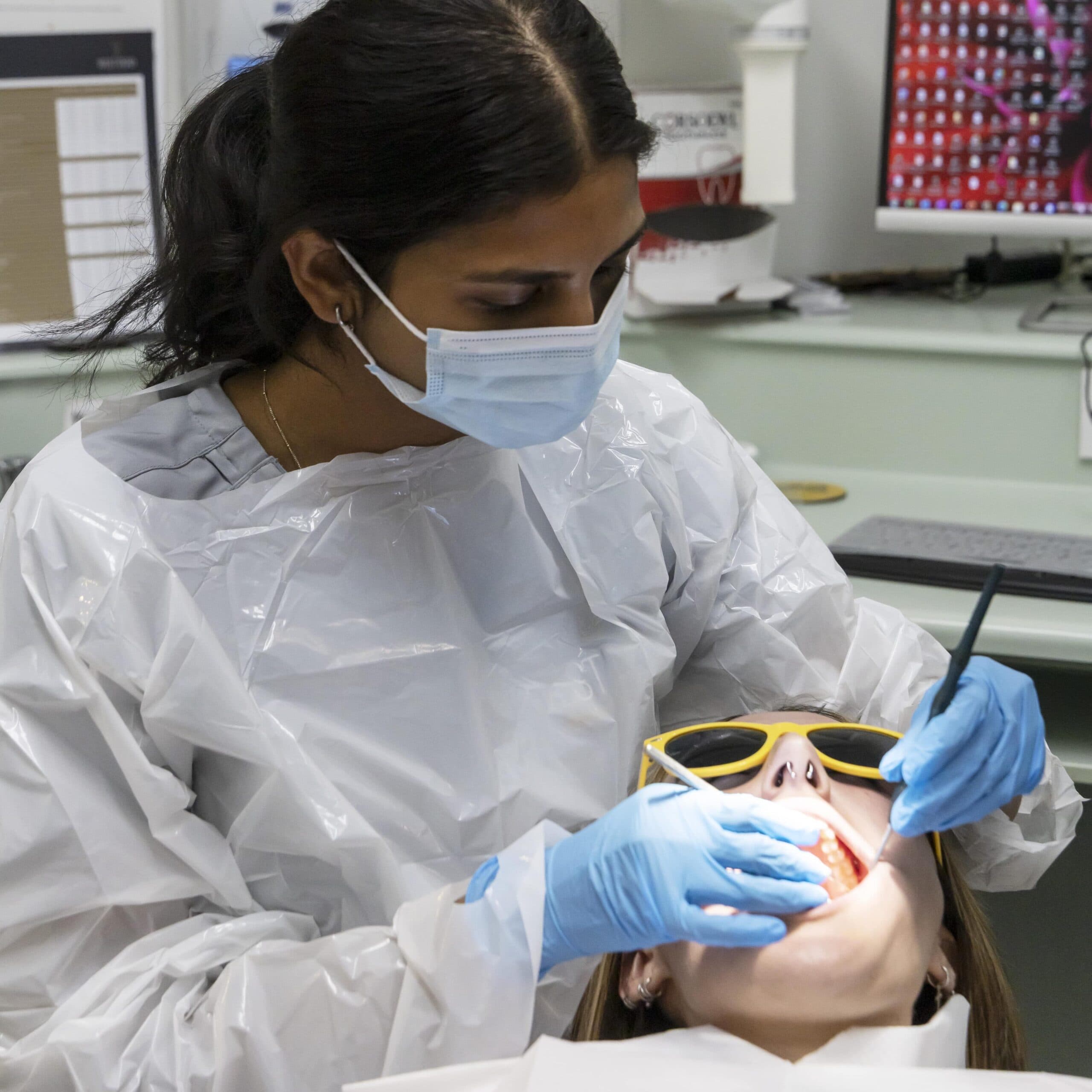 A West Road Dental clinician in a protective gown treating a patient in the Oakham surgery