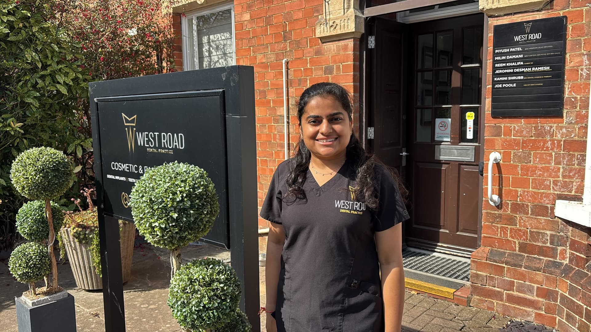 The entrance to West Road Dental Practice on West Road, Oakham — a red brick building with a dark wood door, the practice's black and gold sign outside and the clinicians' nameplate beside the door